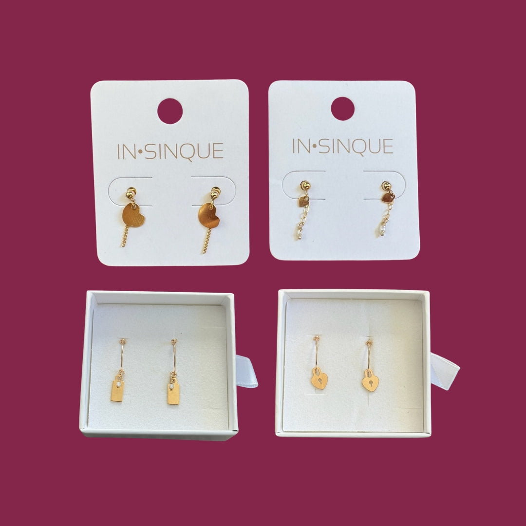 Four pairs of gold earrings on white cards with 'IN SINIQUE' branding against a purple background.